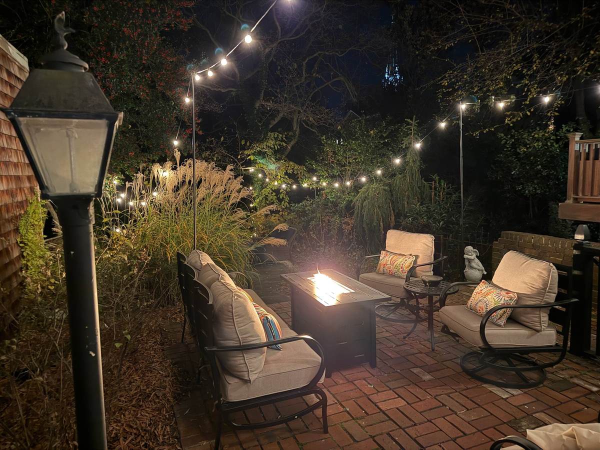 Private back garden with fire pit and string lights at night